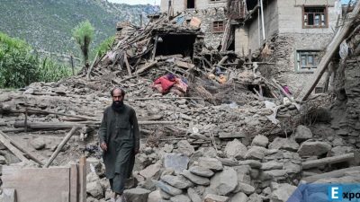 Seorang pria Afghanistan berjalan melewati sebuah rumah yang rusak akibat gempa bumi