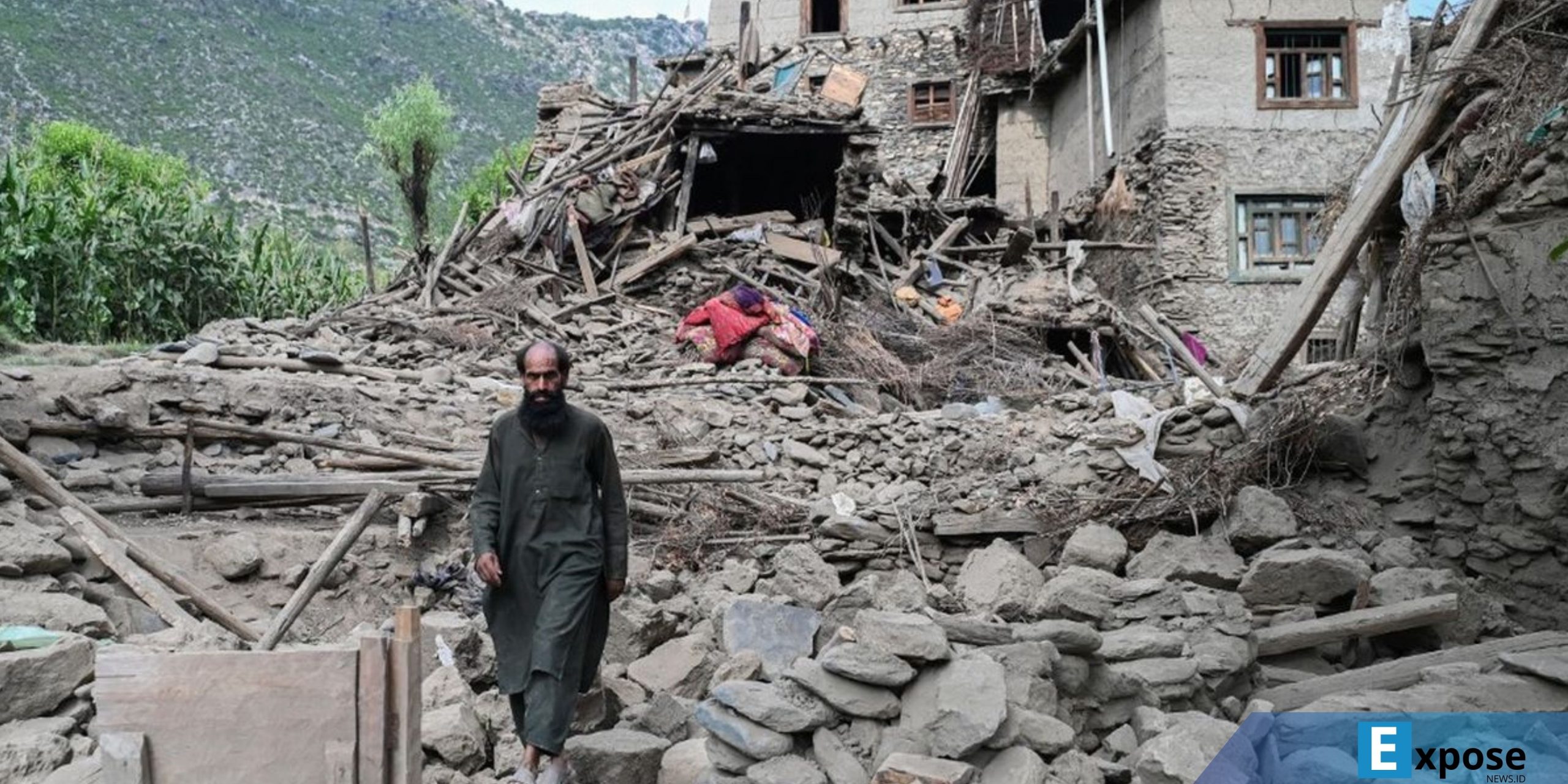 Seorang pria Afghanistan berjalan melewati sebuah rumah yang rusak akibat gempa bumi
